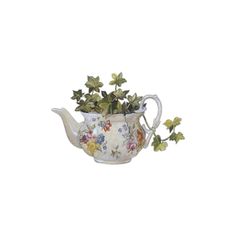 a white tea pot filled with flowers on top of a table