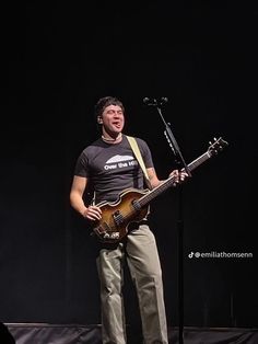 a man standing on top of a stage holding a guitar