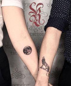 two people holding hands with tattoos on them