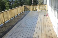 there is a wooden deck with railings on the side of this house and trees in the background