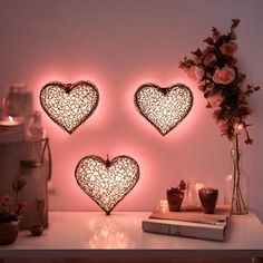 three heart shaped lights on a table next to some flowers and vases with candles