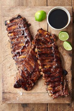 two ribs on a cutting board with limes and a cup of coffee