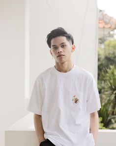 a young man wearing a white t - shirt and black shorts sitting on a ledge