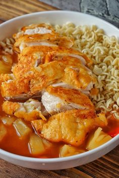 a white bowl filled with pasta and meat covered in gravy on top of a wooden table