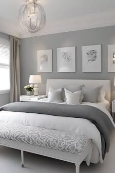 a white and gray bedroom with pictures on the wall above the bed, along with two nightstands