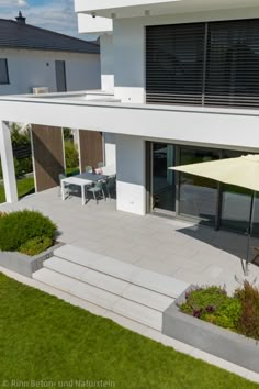 an aerial view of a modern house with patio furniture and umbrellas on the lawn