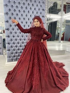 a woman in a red wedding dress standing next to a wall with an intricate pattern on it