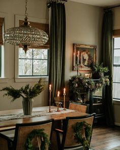 a dining room table with candles and greenery