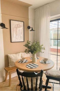 a dining room table with two chairs and a potted plant