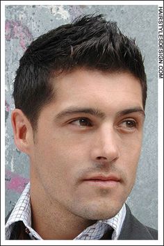 a man in a suit and tie standing next to a wall with graffiti on it