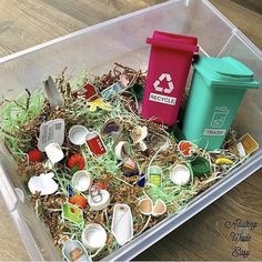 a plastic container filled with assorted items on top of a wooden floor next to a trash can