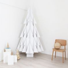 a white christmas tree sitting next to a wooden chair