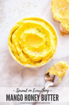 a bowl filled with mango honey butter next to two pieces of bread on a table