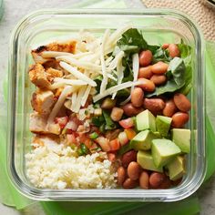 a plastic container filled with rice, beans and avocado on top of a table