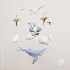 an ornament hanging from a ceiling with stars and clouds in the shape of a dolphin