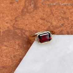 14KT yellow gold bezel-set octagonal/ emerald-cut Mozambique red garnet + accent diamond ring. Stunning, deep red color! Garnet is the birthstone for January babies- and this piece makes a birthstone ring/ engagement ring! Since this is a custom piece, each garnet will vary slightly from stock photo. Can also be made with a different gemstone instead of garnet- please reach out for pricing, as it varies on each gemstone. Size 7 Can be resized for an additional fee Weight: 4.00 grams Band width: Yellow Gold Emerald Cut Ruby Ring Gift, 14k Gold Jewelry With Asscher Cut Gemstone, Emerald Cut Ruby Ring With Accent Stones As Gift, Fine Jewelry Garnet Ruby Ring With Bezel Setting, 14k Gold Jewelry With Emerald Cut Gemstone Accents, Octagon Birthstone Ring With Gemstone For Gifts, Emerald Cut Gemstone Jewelry In 14k Gold, Emerald Cut Gemstone Accents 14k Gold Jewelry, Emerald Cut 14k Gold Jewelry With Gemstone Accents