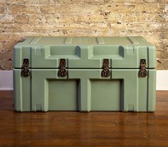 two green coolers sitting on top of a wooden floor next to a brick wall