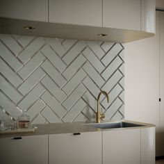 a kitchen with white cabinets and a gold faucet