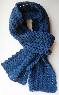 a blue crocheted scarf laying on top of a white table