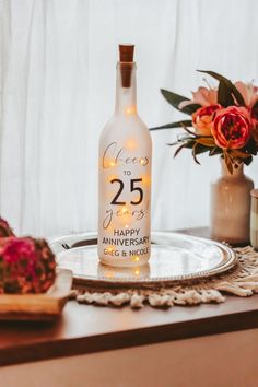 a bottle of wine sitting on top of a table next to some flowers and candles