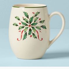 a white coffee cup with holly decorations on it