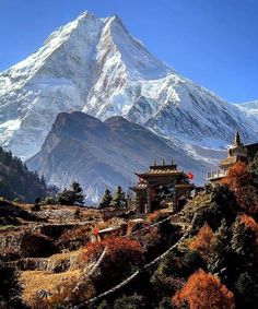 the mountain is covered in snow and has a pagoda on it's side, surrounded by trees