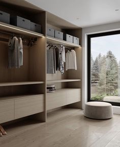 a large walk in closet with lots of drawers and clothes hanging on the shelves next to a window