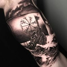 a man's arm with a ship in the ocean and compass tattoo on it