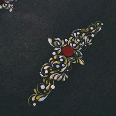 a close up of an embroidered object on a black surface with white and yellow designs