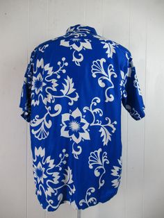 "Vintage 1960s blue and white cotton Hawaiian shirt. Has a matching pattern chest pocket, brass button front, top loop collar button and straight cut hem. Label reads: CREATED IN HAWAII FOR DIAMOND HEAD SPORTSWEAR. Size large. Measurements are: 45\" around the chest 45\" around the waist 18\" shoulder seam to shoulder seam 30\" overall length In very good condition." Blue Hawaiian Shirt With Floral Print And Camp Collar, Blue Printed Button-up Hawaiian Shirt, Blue Printed Hawaiian Button-up Shirt, Blue Floral Print Button-up Hawaiian Shirt, Blue Floral Print Hawaiian Button-up Shirt, Blue Printed Button-up Camp Shirt, Retro Blue Cotton Hawaiian Shirt, Blue Collared Hawaiian Shirt With Floral Print, Blue Cotton Hawaiian Shirt With Hibiscus Print