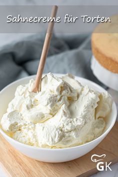 a white bowl filled with whipped cream on top of a wooden cutting board