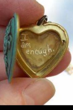 a tiny heart shaped locke with the words i am enough written on it