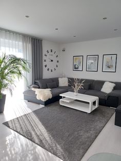 a living room filled with furniture next to a large window covered in white and gray curtains