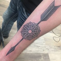 an arrow and flower tattoo on the arm