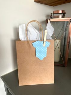 a brown paper bag with a blue polka dot baby onesie on it sitting on a table