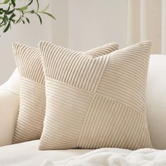 two pillows sitting on top of a white couch next to a potted green plant