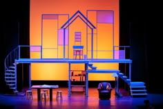 the stage is lit up with blue lighting and furniture in front of an orange background