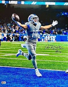 an autographed photograph of a football player catching a ball in the air with his arms outstretched