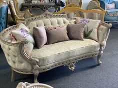 an ornate couch with many pillows on it in a room filled with furniture and mirrors