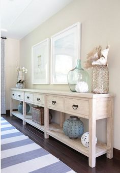 a white table with two vases on top of it next to a blue and white striped rug