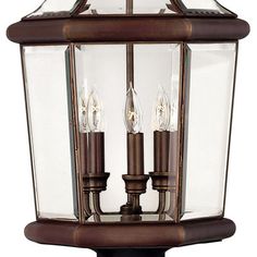 an outdoor light with three lights on it's sides and two candles in the middle