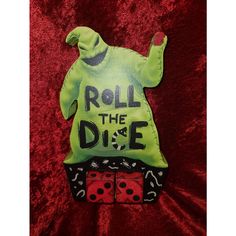 a green shirt that says roll the dice on top of two red dice holders in front of a red velvet background