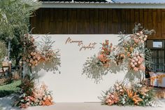 an outdoor wedding setup with flowers and greenery on the wall, surrounded by palm trees