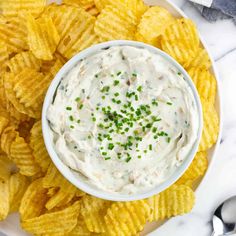 a white plate topped with chips covered in ranch dip surrounded by green sprinkles