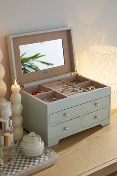 an open jewelry box sitting on top of a table next to candles and other items