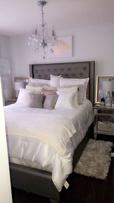 a bedroom with a large bed and chandelier hanging from the ceiling, along with a rug on the floor