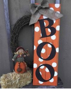 a wooden sign with the word boo on it next to a scarecrow and pumpkin