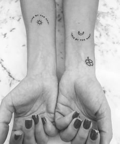 two people holding hands with tattoos on their wrists and fingers, both showing the same symbol