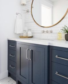 a bathroom with blue cabinets and a round mirror