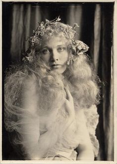 an old black and white photo of a woman with long blonde hair wearing a flower crown